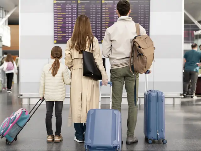 Familia con maletas frente al tablero de vuelos de un aeropuerto