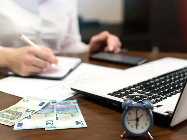 Persona organizando sus finanzas con laptop y documentos